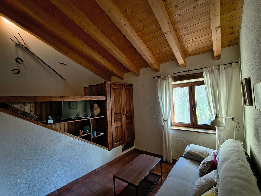 Salón comedor con sofá cama y vistas a la montaña en el refugio pirenaico Casa Puixico.