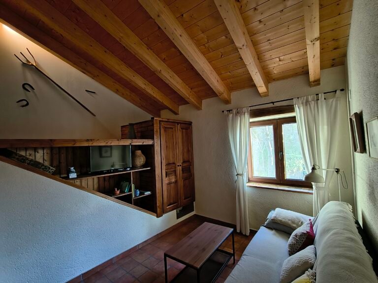 Salón comedor con sofá cama y vistas a la montaña en el refugio pirenaico Casa Puixico.