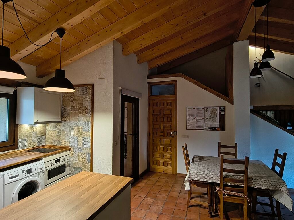Cocina y comedor abiertos de diseño rústico integrado en la casa rural Casa Puixico.