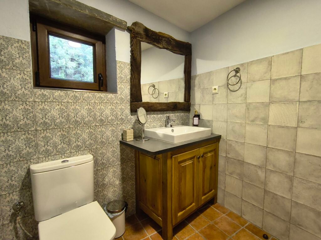 Baño moderno con ducha y acabados rústicos en casa de montaña en el Pirineo aragonés.